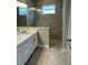 Clean bathroom with gray tile, a walk-in shower, and white vanity at 24732 Buckingham Way, Port Charlotte, FL 33980