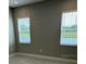 Simple bedroom with neutral walls and two large windows at 24732 Buckingham Way, Port Charlotte, FL 33980