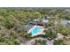 Aerial view of community pool, tennis courts surrounded by lush greenery and mature trees, with golf carts nearby at 3375 Sandleheath # 34, Sarasota, FL 34235