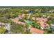 Aerial view showcasing a community with pools, mature trees, and manicured landscaping with a glimpse of a pond at 3375 Sandleheath # 34, Sarasota, FL 34235