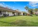 Exterior showcases green lawn, mature tropical landscaping, and neutral stucco with a tiled roof under a blue sky at 3375 Sandleheath # 34, Sarasota, FL 34235