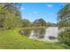 Scenic view of the pond from the shoreline with the reflection of trees on the water and a clubhouse at 3375 Sandleheath # 34, Sarasota, FL 34235