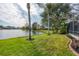 Serene backyard featuring lush green lawn, mature trees, and tranquil lake views at 455 Park Trace Blvd, Osprey, FL 34229