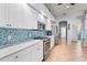 Bright kitchen featuring stainless steel appliances, white cabinetry, and a blue tile backsplash at 132 Shady Pkwy, Sarasota, FL 34232