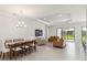 Open concept living room and dining area features a tray ceiling, tile floors, and sliding glass doors at 10128 Morning Mist Ln, Sarasota, FL 34241