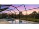 Sparkling swimming pool and hot tub with a screened enclosure overlooking lush landscaping at dusk at 2129 Lorraine Dr, Port Charlotte, FL 33953