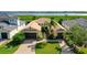 Aerial view of a single-story home with a terracotta roof, a large lawn and waterfront in the background at 5706 Tidewater Preserve Blvd, Bradenton, FL 34208