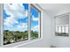 Bedroom featuring large windows providing stunning views of palm trees, clear blue sky, and city buildings at 800 N Tamiami Trl # 307, Sarasota, FL 34236