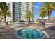 Relaxing hot tub surrounded by palm trees and a swimming pool, near residential building and lounge furniture at 800 N Tamiami Trl # 307, Sarasota, FL 34236