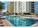 Large swimming pool surrounded by lounge chairs with high-rise buildings in the background under a bright sky at 800 N Tamiami Trl # 307, Sarasota, FL 34236