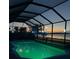 Lighted screened pool at night with lake view at 13421 Orino St, Venice, FL 34293