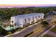 Aerial view of modern apartment building with a pool, lush trees, and serene waterfront setting during sunset at 4950 Remington Dr # 407, Sarasota, FL 34234