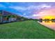 Expansive backyard with lush green lawn and scenic lake view, enhanced by a screened pool enclosure at 8332 Sea Glass Ct, Sarasota, FL 34240