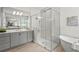 Elegant bathroom featuring a soaking tub, frameless glass shower, dual sinks, and wood look tile floors at 8332 Sea Glass Ct, Sarasota, FL 34240
