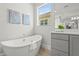 Bright bathroom featuring a soaking tub with a large window and gray shaker cabinets at 8332 Sea Glass Ct, Sarasota, FL 34240