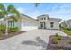 Beautiful home featuring a three-car garage, light exterior, and paver driveway surrounded by lush landscaping at 8332 Sea Glass Ct, Sarasota, FL 34240