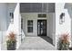 A welcoming front entrance with sleek black door, modern lighting, and beautiful potted plants at 8332 Sea Glass Ct, Sarasota, FL 34240