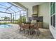 Outdoor kitchen area, featuring a built-in grill, dining table, and view of the swimming pool at 8332 Sea Glass Ct, Sarasota, FL 34240