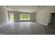 An empty living room featuring modern gray floors, a large window with views, and access to a backyard patio at 3249 Vickers Ln, North Port, FL 34286