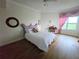 Bedroom features hardwood floors, and a large window with pink curtains at 5450 Eagles Point Cir # 405, Sarasota, FL 34231