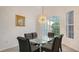 Dining room with glass table and modern chandelier, large windows at 9506 Royal Calcutta Pl, Lakewood Ranch, FL 34202