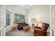 Study with leather furniture, wicker side table, and large windows at 9506 Royal Calcutta Pl, Lakewood Ranch, FL 34202