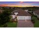 Two-story house with a brick driveway and a three-car garage, at sunset at 13627 American Prairie Pl, Lakewood Ranch, FL 34211
