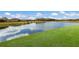 Serene pond with a grassy area and houses in the background at 13627 American Prairie Pl, Lakewood Ranch, FL 34211