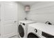 Functional laundry room equipped with modern washer, dryer, and storage shelving for convenience at 2400 Ezzell Ct, Sarasota, FL 34237