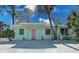 Front view of a charming light green house with a pink door at 321 Hills Rd, Nokomis, FL 34275