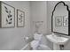 Elegant powder room with pedestal sink, corner toilet, and framed art at 403 Bow Ln, Bradenton, FL 34208