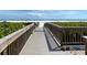 Wooden boardwalk leads to beach with umbrellas and people at 5760 Midnight Pass Rd # 307D, Sarasota, FL 34242