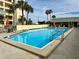 Community pool with lounge chairs, tables, umbrellas, and a view of the building at 5770 Midnight Pass Rd # 705C, Sarasota, FL 34242