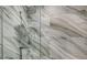 Elegant shower with marble-like tile and glass enclosure at 62 Audubon Pl, Sarasota, FL 34237