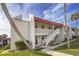 White building with red roof, stairs, and palm trees at 1801 Gulf N Dr # 222, Bradenton Beach, FL 34217
