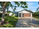 Modern home exterior with a wood-paneled garage door and well-manicured lawn at 1899 Buccaneer Cir, Sarasota, FL 34231