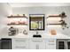 Modern wet bar with floating shelves, wine cooler, and quartz countertop at 1899 Buccaneer Cir, Sarasota, FL 34231