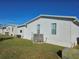 White manufactured home with a grassy yard and AC unit at 3404 Overcup Oak Ter, Sarasota, FL 34237