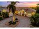 Luxury home with tile roof, palm trees, and a brick driveway at sunset at 4964 Bella Terra Dr, Venice, FL 34293