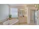 Elegant bathroom features a soaking tub, vanity, and glass block window at 7615 Windward Cv, Lakewood Ranch, FL 34202