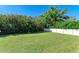 A spacious grassy backyard bordered by lush greenery and a white fence offers privacy at 220 Monet Dr, Nokomis, FL 34275