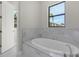 Bathroom with free-standing bathtub and marble tile surround at 4672 Mondrian Ct, Sarasota, FL 34240