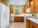 Kitchen with wood cabinets, white appliances, and a pass-through at 6642 Tailfeather Way, Bradenton, FL 34203