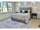 Gray upholstered bed, nightstands, and rug in bright bedroom with large windows at 8324 Golden Beach Ct, Parrish, FL 34219