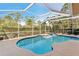 Inviting screened-in pool area with spa and mature landscaping, perfect for relaxing and entertaining outdoors at 3623 Monday Ter, North Port, FL 34286