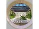 View of a tranquil pond and pergola through a circular window at 1245 Mill Creek Rd, Bradenton, FL 34212