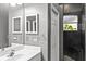 Bathroom with double sinks, white cabinets, and enclosed black tile shower at 2063 Lynx Run, North Port, FL 34288