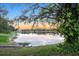Scenic pond view reflecting the sunset sky, surrounded by lush greenery and mature trees at 2063 Lynx Run, North Port, FL 34288