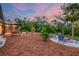 Landscaped backyard with firepit, seating area, and natural surroundings at sunset at 220 Ciboa Ave, North Port, FL 34287