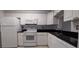 Compact kitchen with white cabinets, black countertops, and white appliances at 7294 Cloister Dr # 8, Sarasota, FL 34231